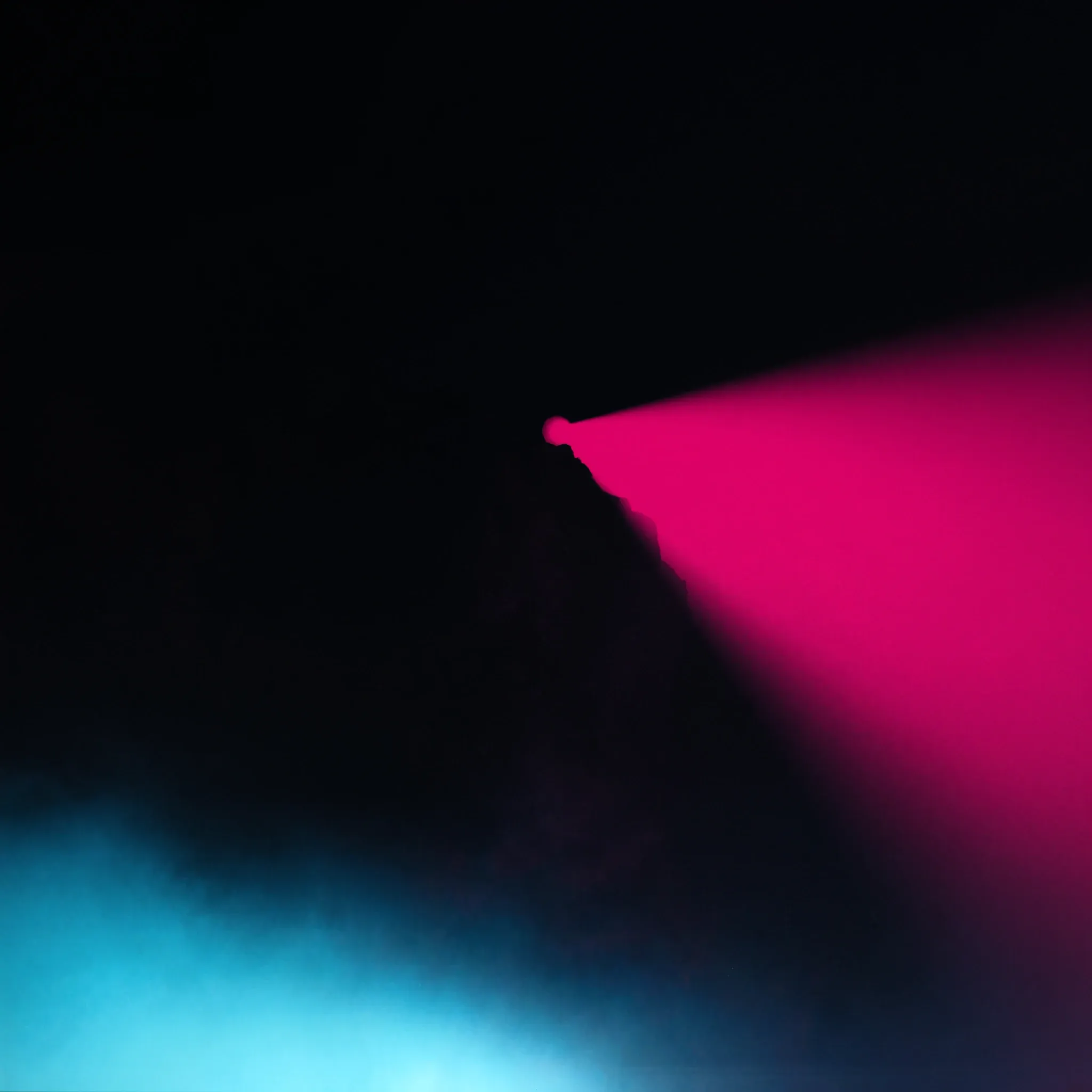 A single beam of light bridging a dark canyon, mist drifting below