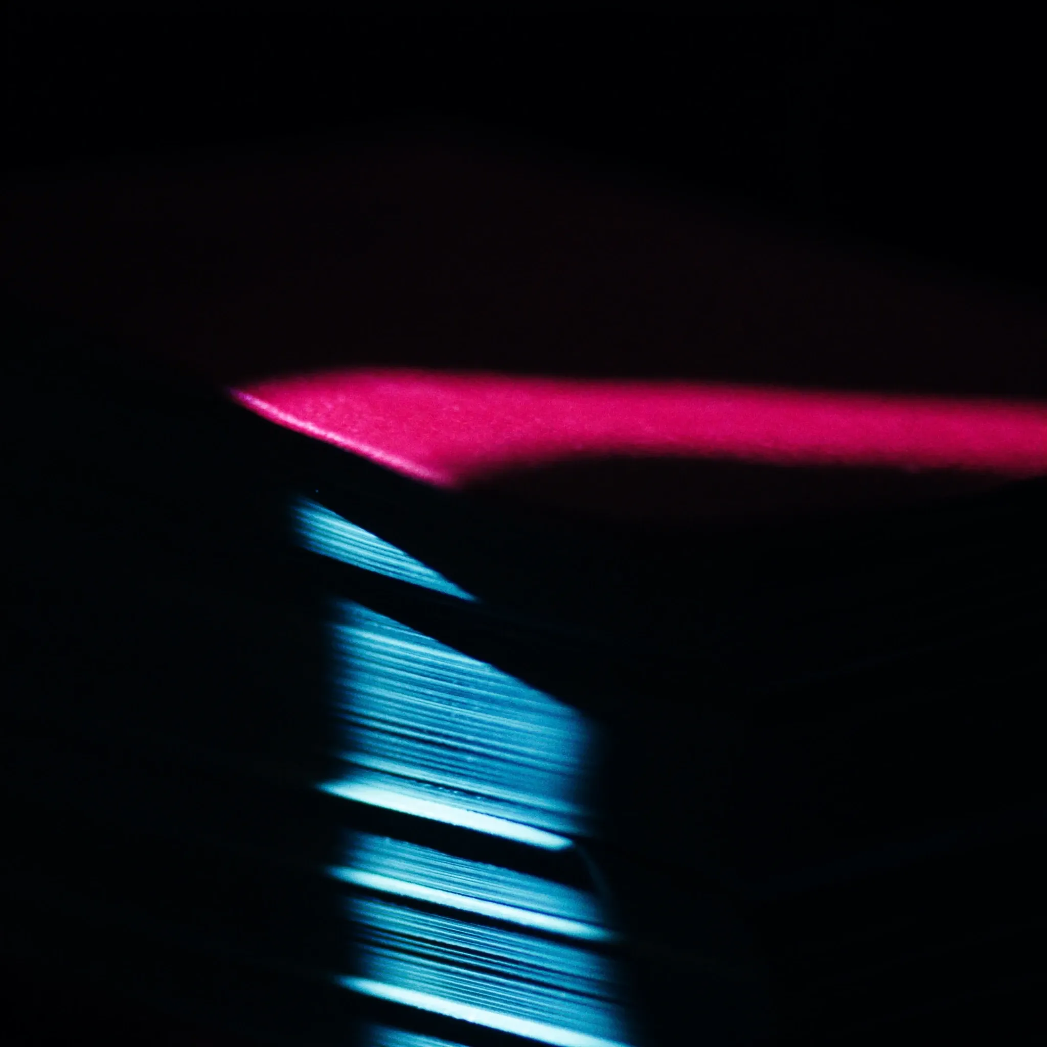 A single beam of light falling across the edge of a thick stack of bound pages, dark and calm