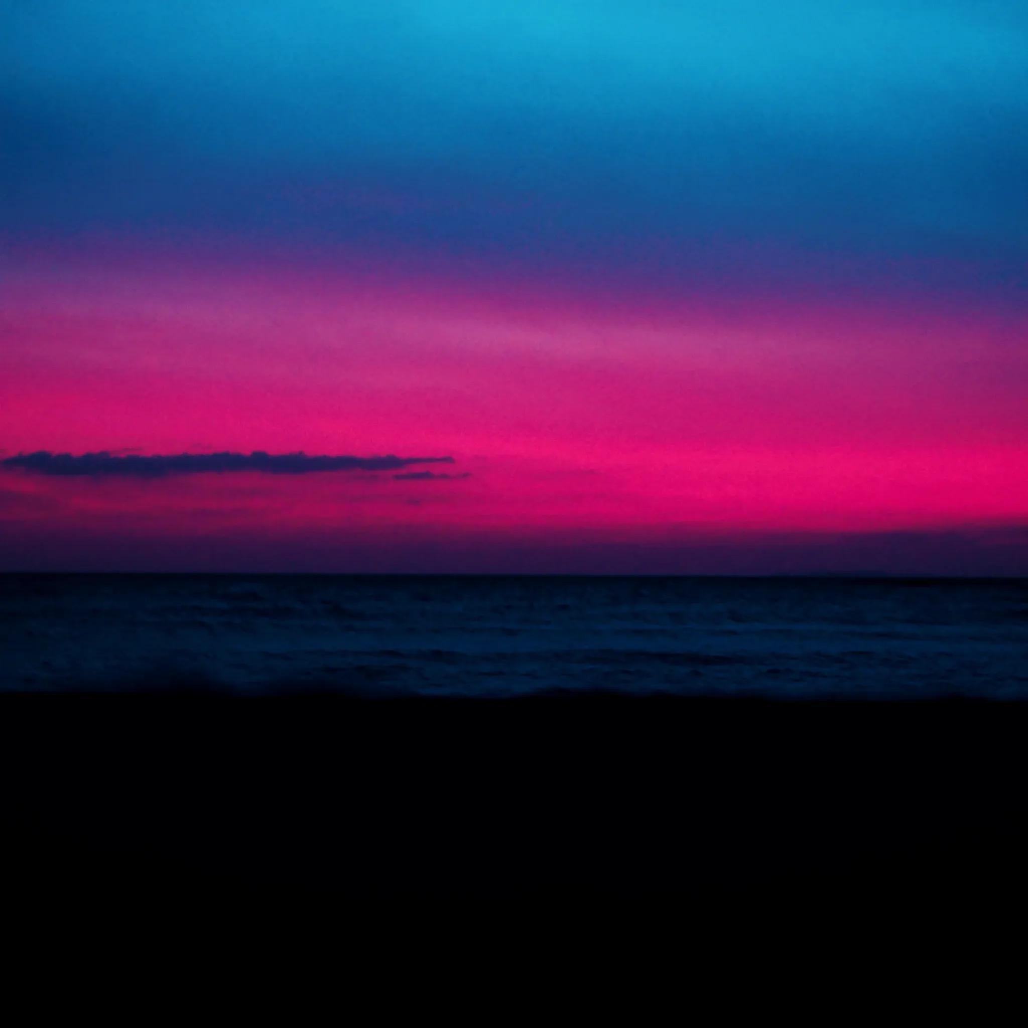 First light over the Atlantic seen from a Cape Town beach, wide open horizon, sky fading from deep blue to pink above calm water, nothing else in frame