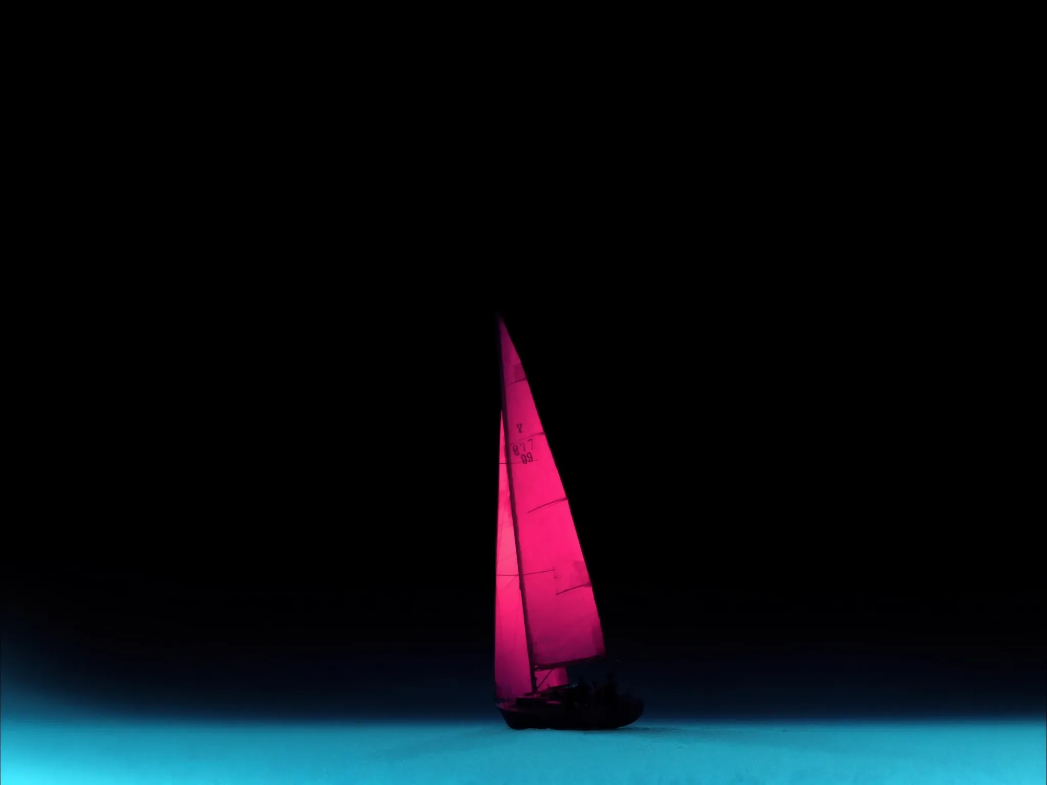 A lone sailboat silhouette far off on calm dark water at dusk, small in the frame, its plain unmarked sail glowing pink