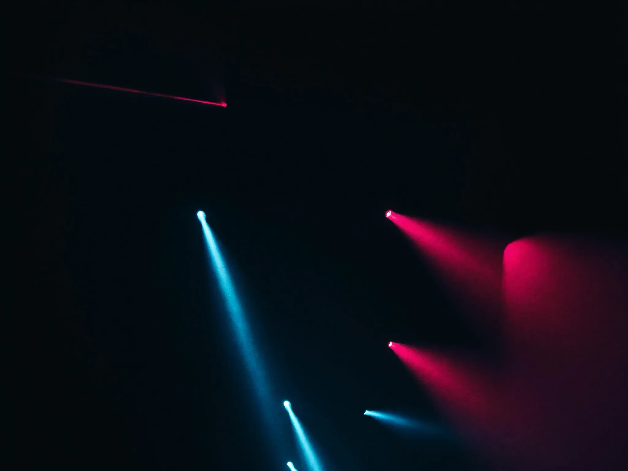 Thin beams of light escaping through several separate cracks in a dark wall, each one pointing a different way