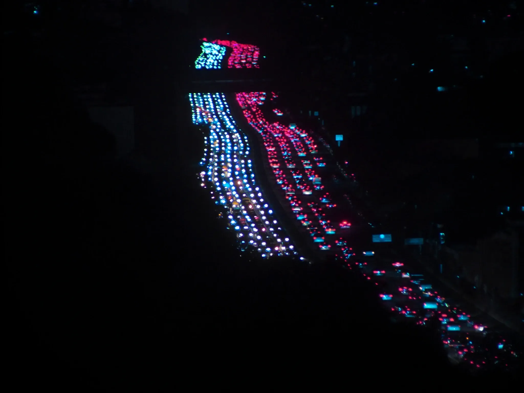 Dense Johannesburg traffic at night seen from above, a packed river of headlights and tail lights