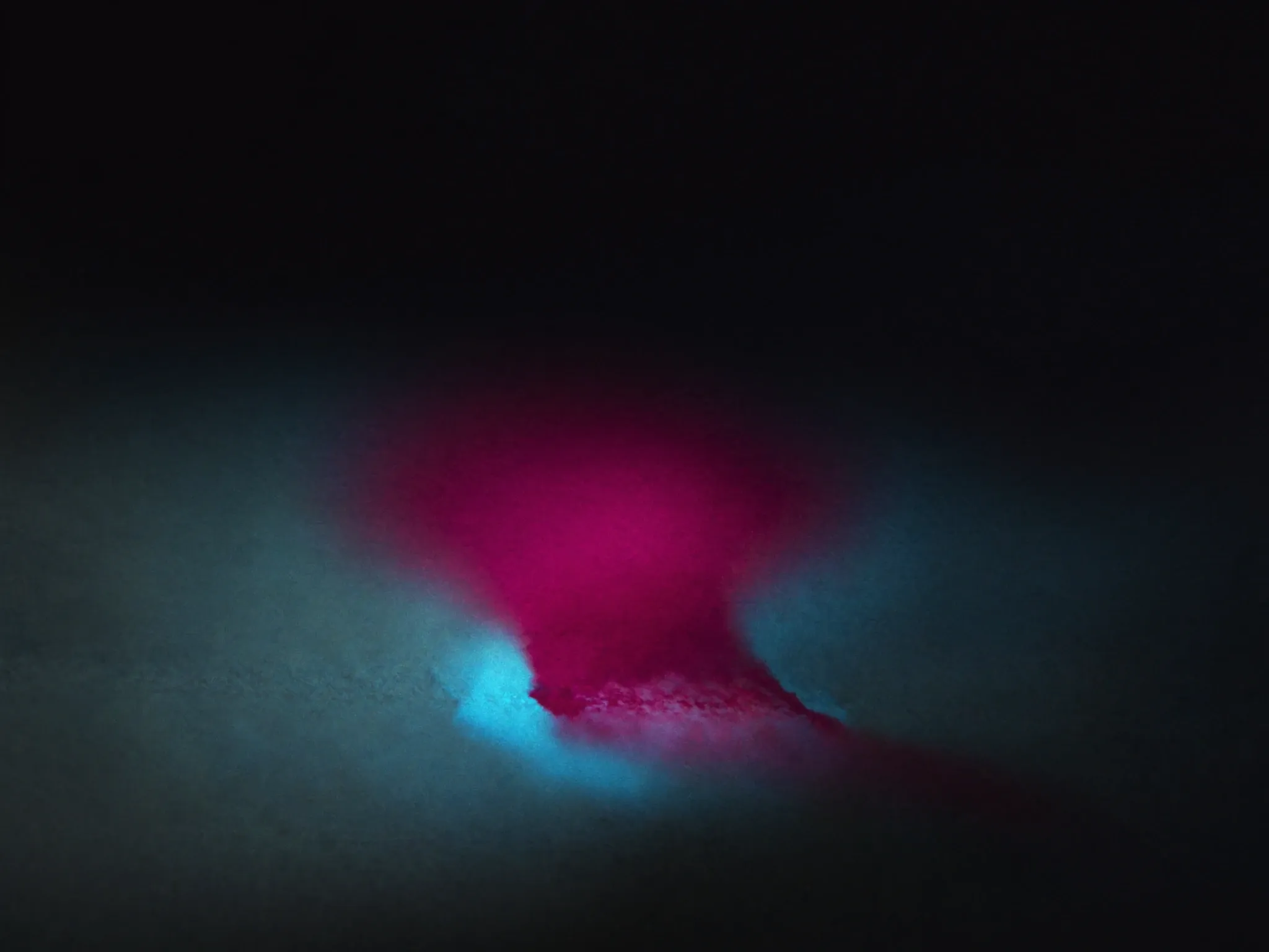 A smudged ink stain bleeding into wet paper, soft-edged and indistinct, magenta on dark grey, macro