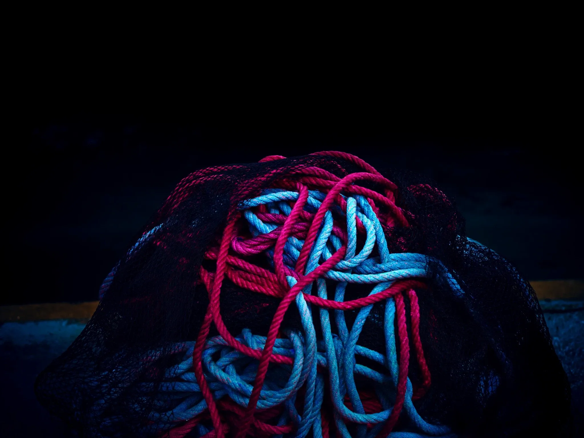 Tangled, knotted fishing ropes and nets piled on the quay at Kalk Bay harbour, Cape Town, at dusk, colourful and impossible to unpick