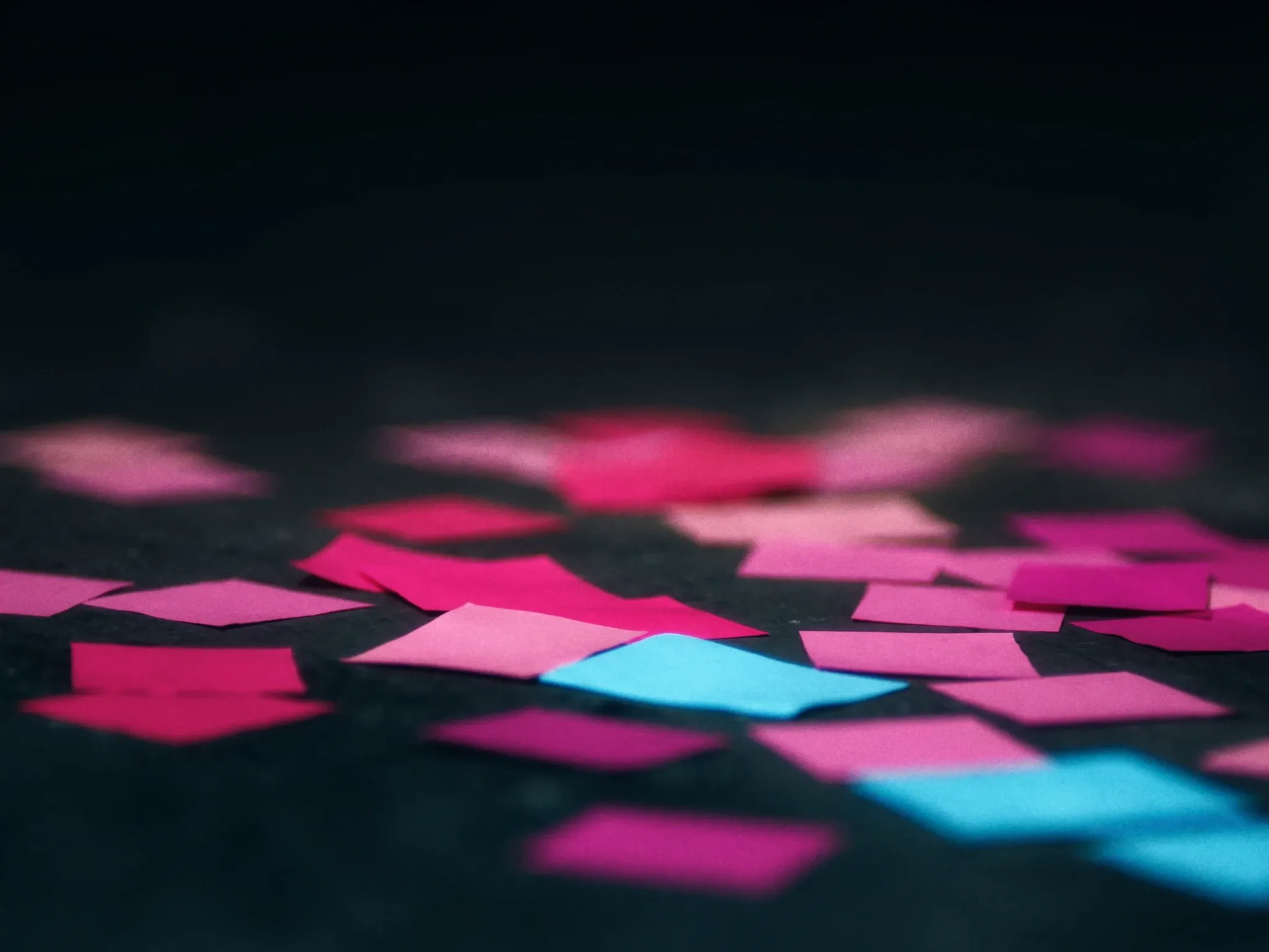 Paint swatches in slightly different shades of pink scattered and overlapping on dark concrete, none of them matching