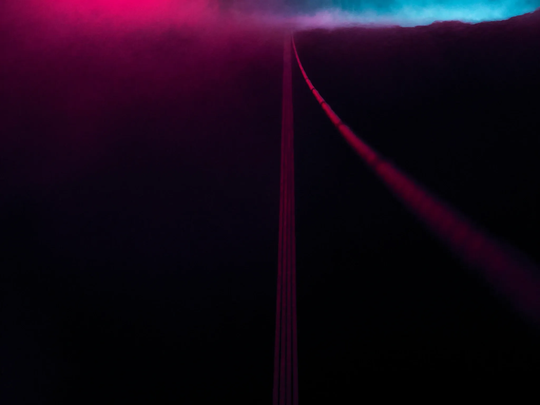 A narrow rope bridge across a misty gorge at dusk, the far side hidden in fog