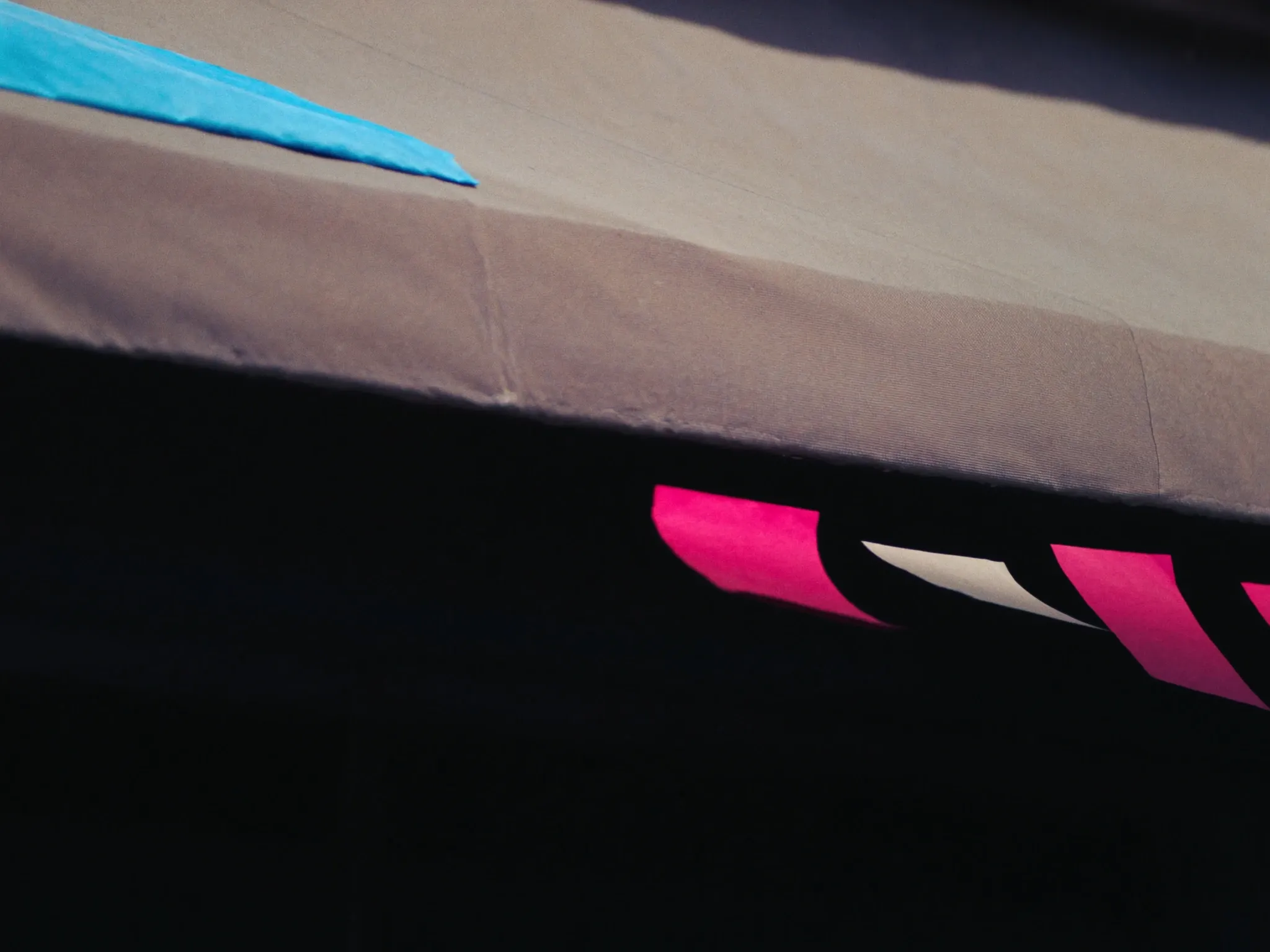 A faded, sun-bleached canvas awning over an empty doorway in late afternoon light, colours washed out, close up, no lettering