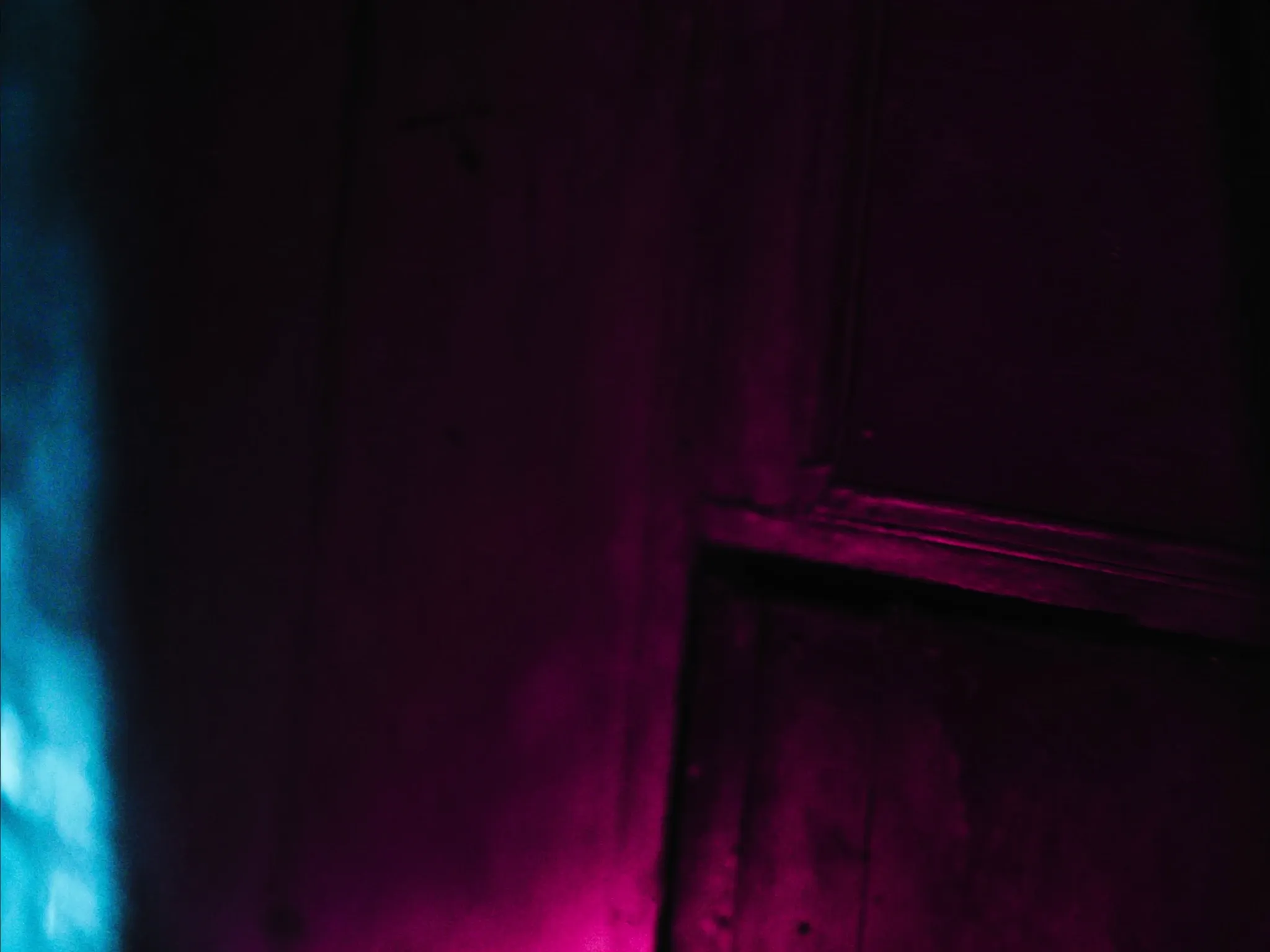 Sun-bleached, faded paint on an old wooden door, the colours washed out, dark and moody close up