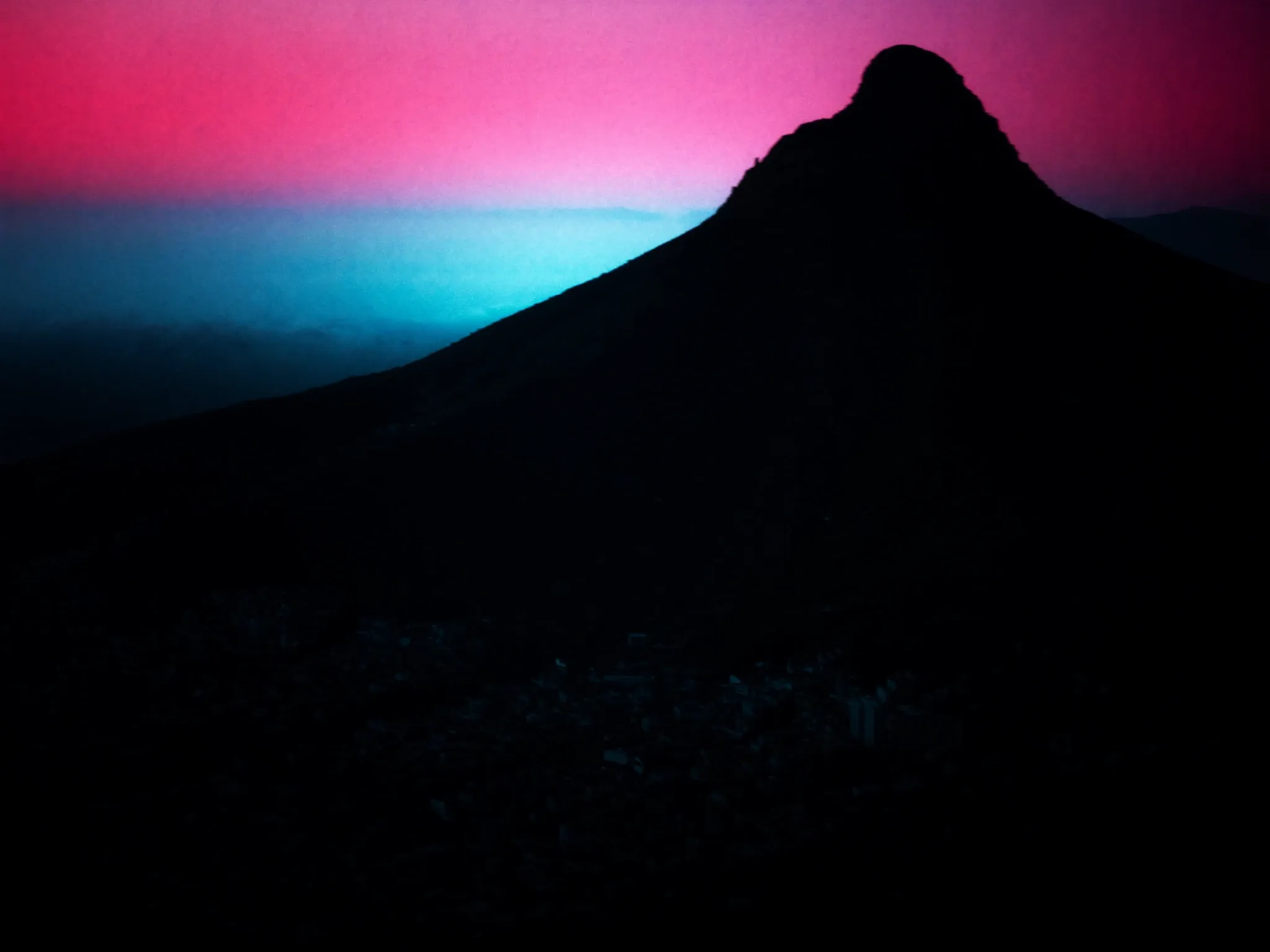Morning mist lifting off Lion's Head, Cape Town, the peak sharp against a soft pink sky, the city still dark below