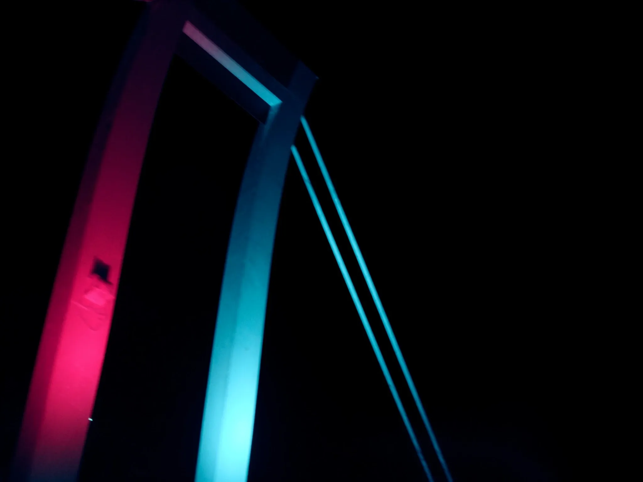 The cable-stayed Nelson Mandela Bridge in Johannesburg at night, its cables lit in cyan and pink against a dark sky, no vehicles, no signage