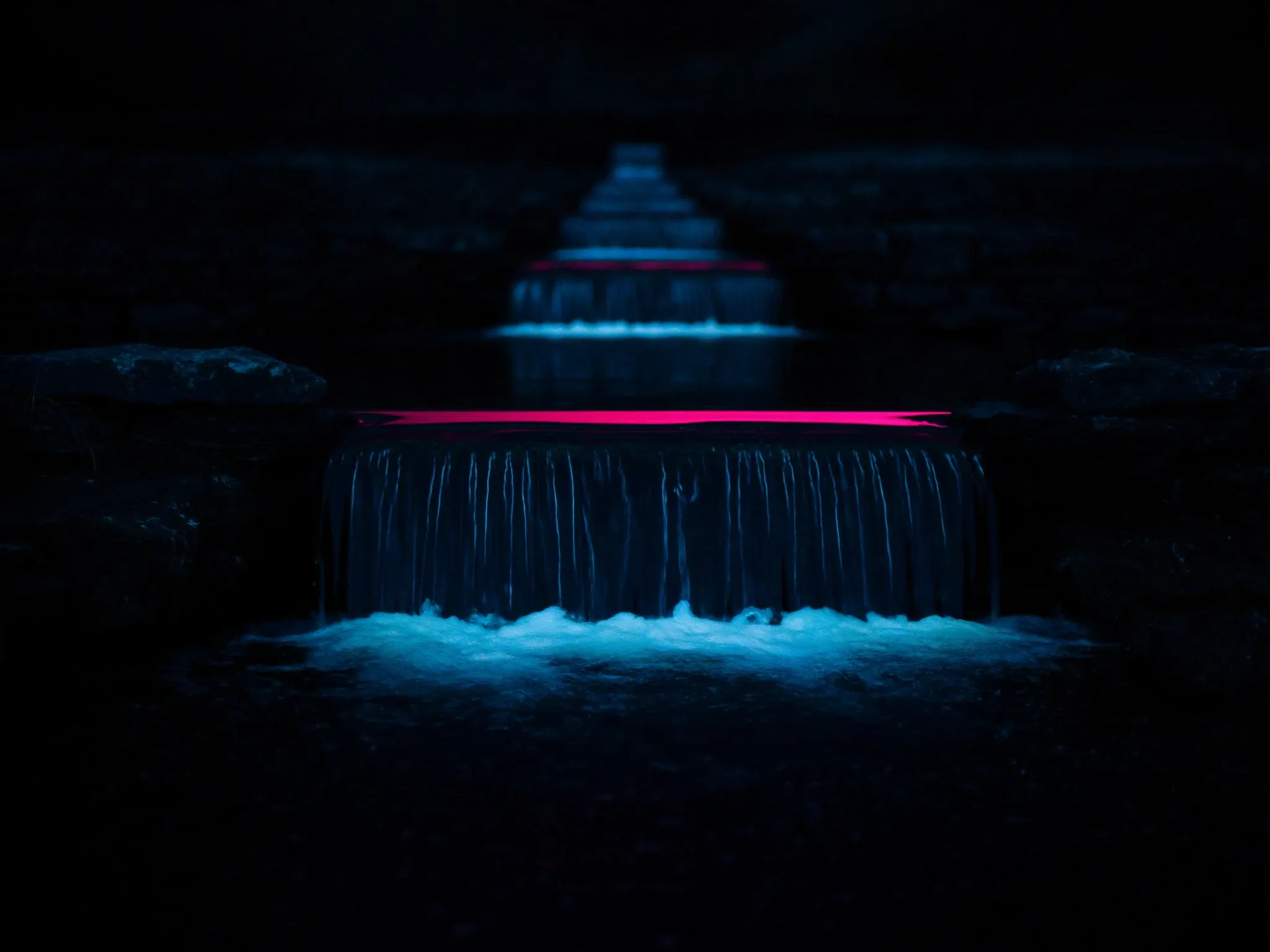 Water channelled through a series of small stone weirs, each level held and released, long exposure, blue hour