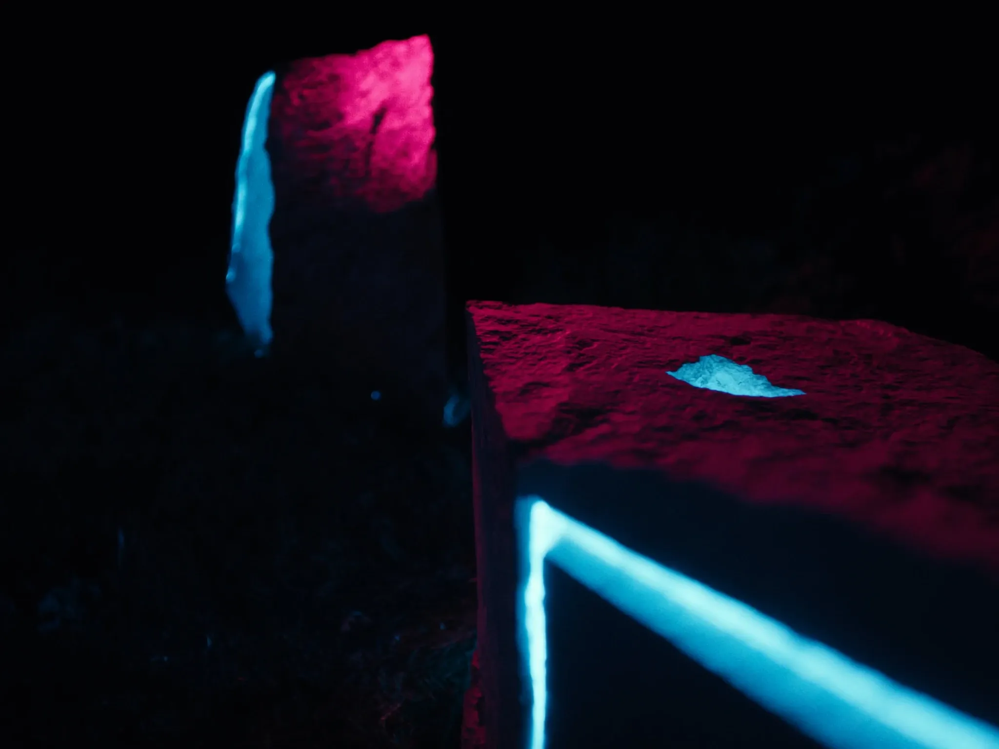 Two different stone structures joined by one precise glowing seam, architectural