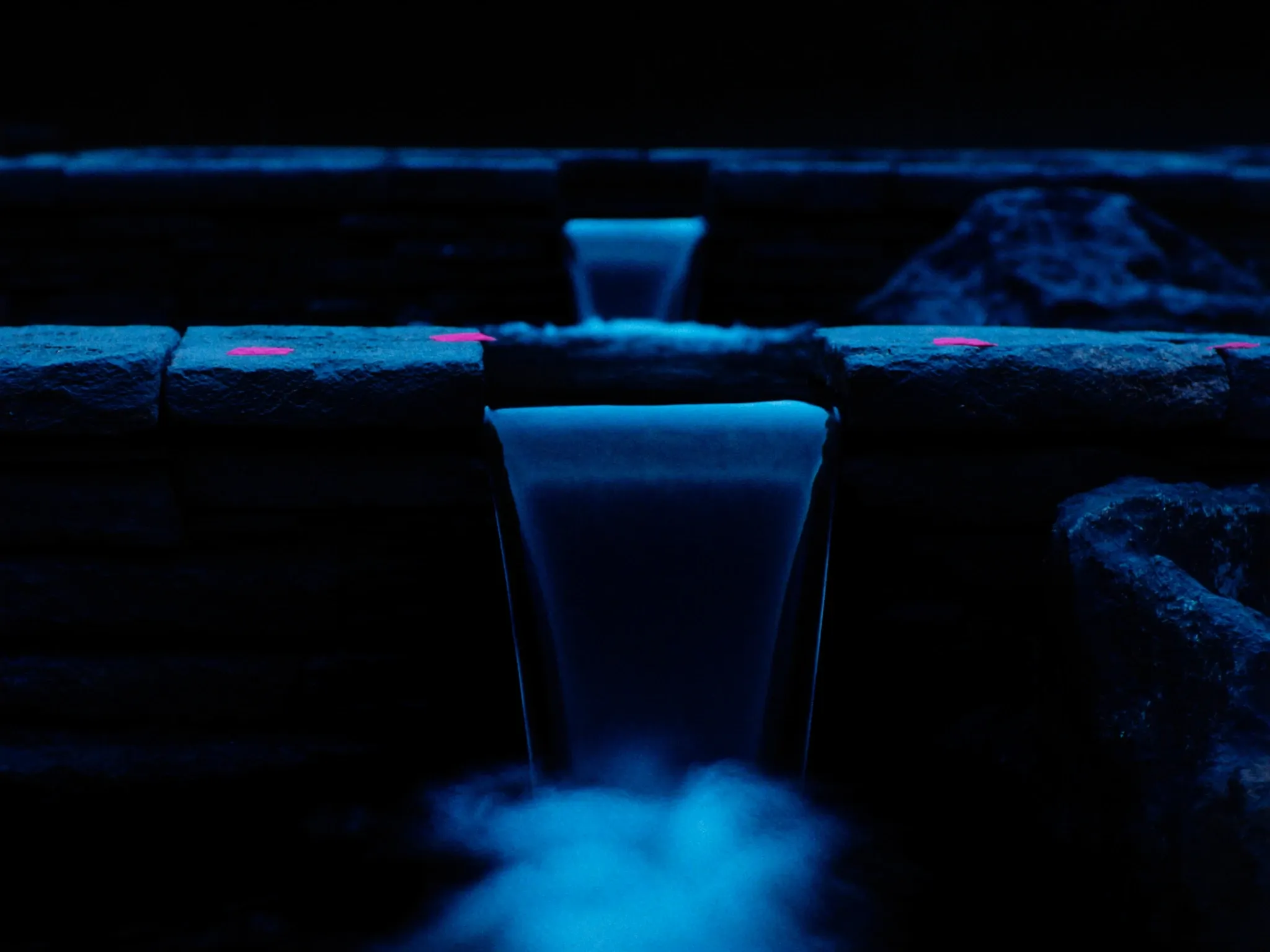 Water flowing between three connected stone pools at different levels, long exposure, blue hour