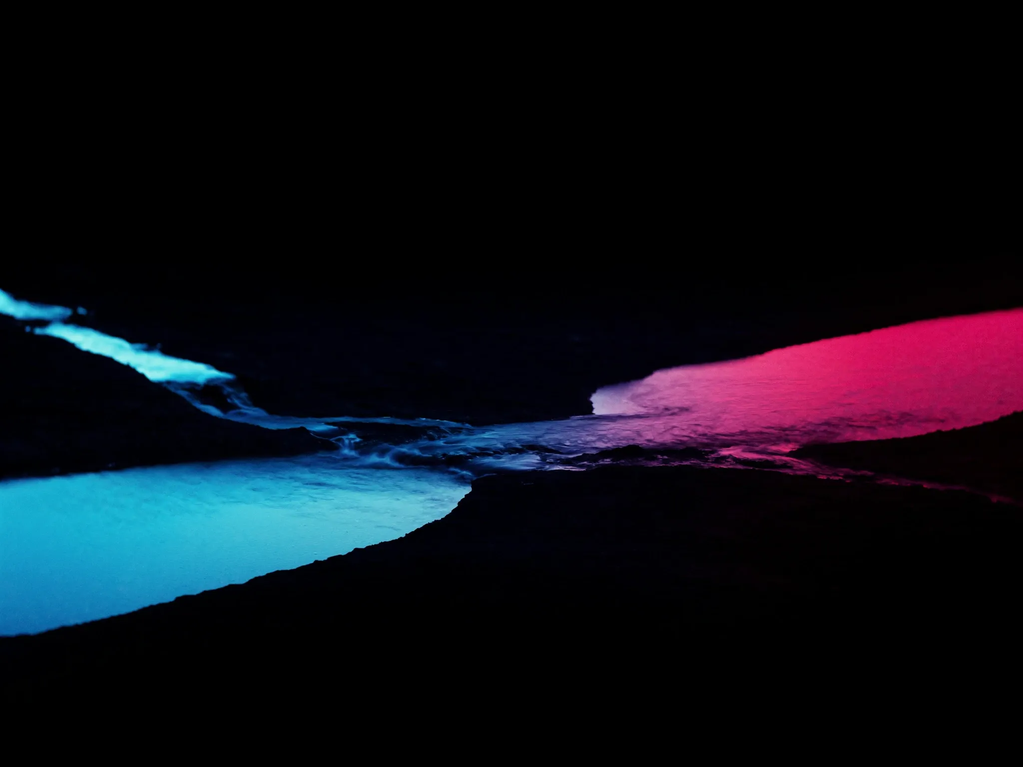 Several small streams running together into one channel across dark rock at a Cape Peninsula tidal pool, long exposure, cool blue with a pink sky reflected