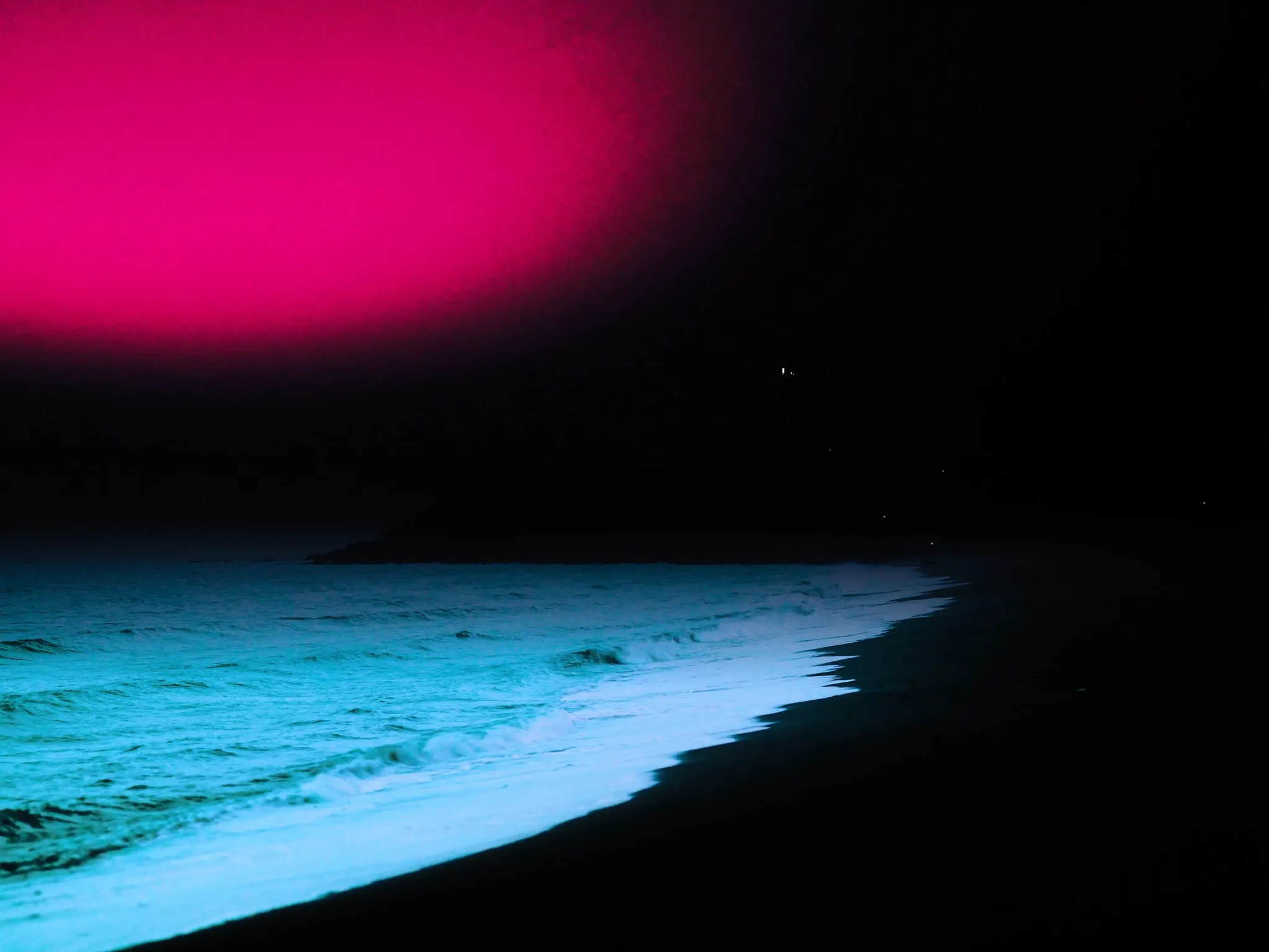 Gentle Indian Ocean waves rolling onto a long empty beach at dawn, a lighthouse a small silhouette in the distance, pink and blue sky