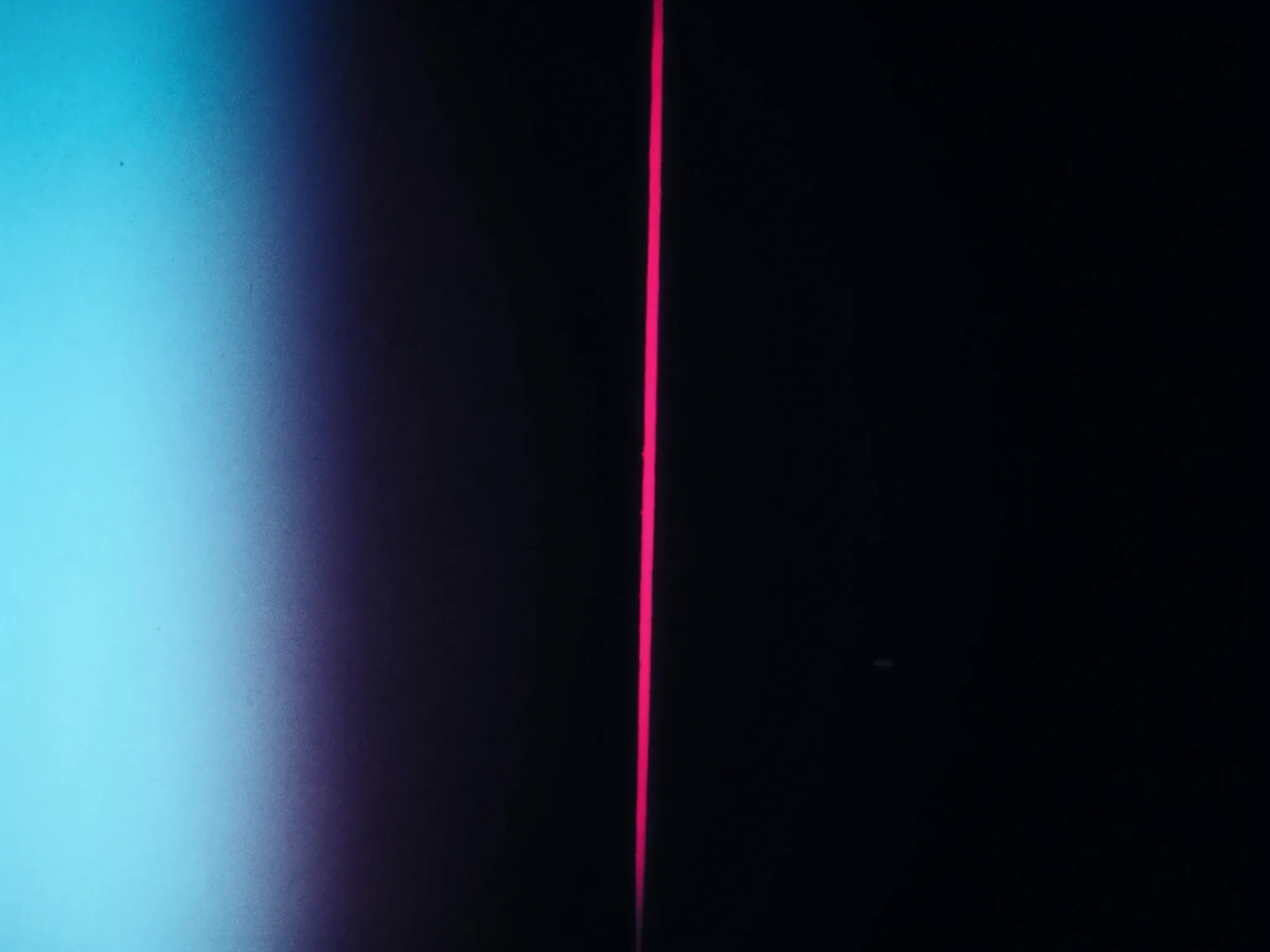 A single vertical sliver of bright light cutting through a dark, hazy space, pink at its edges