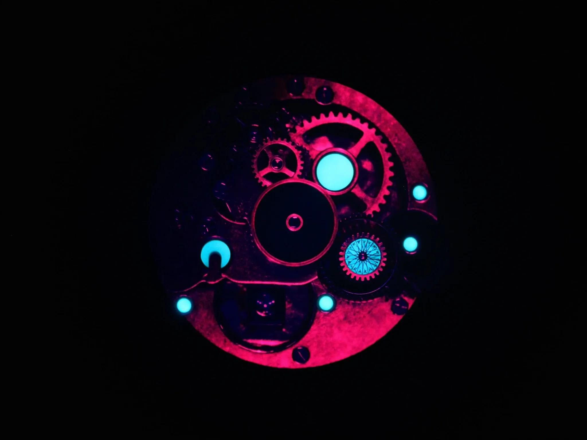 A precise mechanical watch movement in macro, gears and jewels lit pink and cyan