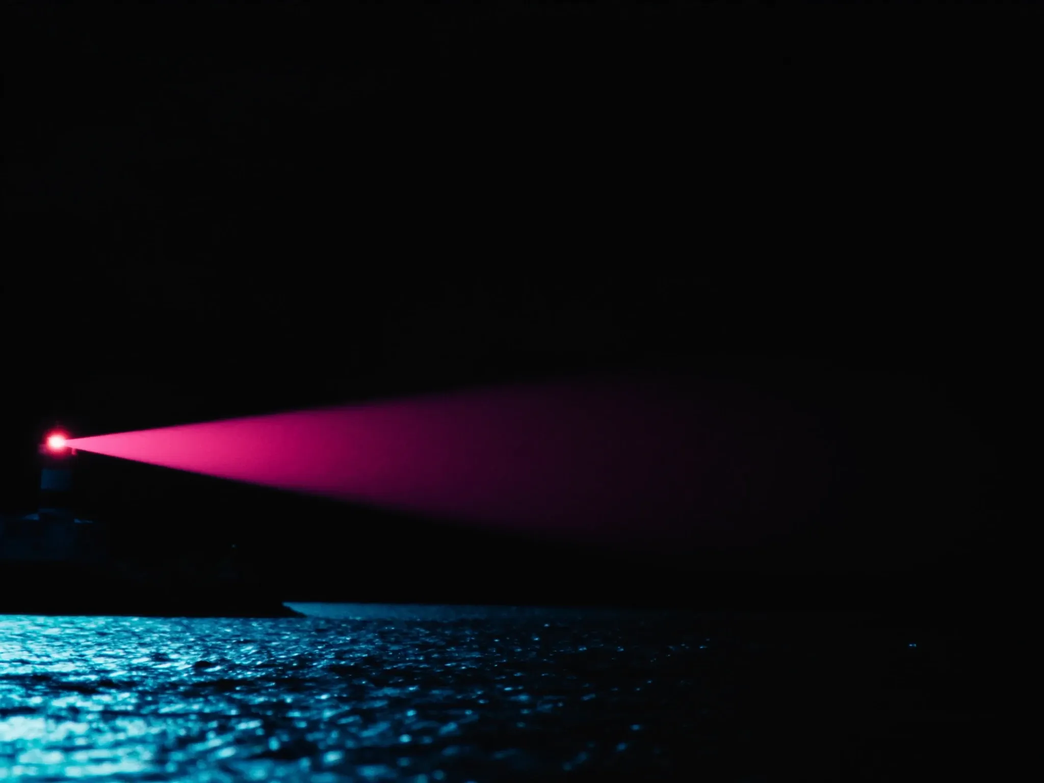 A lighthouse beam sweeping steadily over a dark sea at night