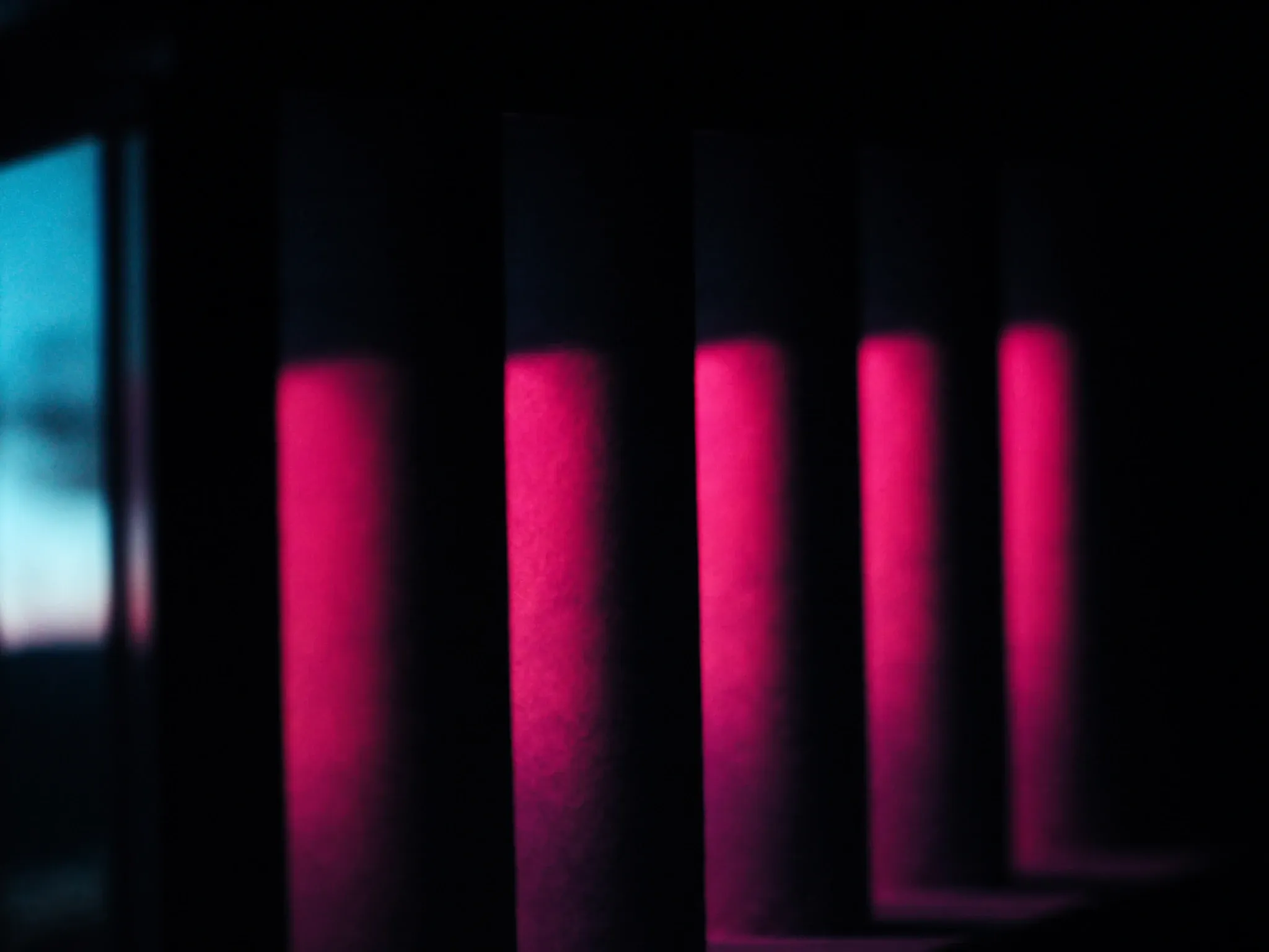 A row of identical stone columns casting even shadows in warm evening light, architectural and minimal, pink and blue tones