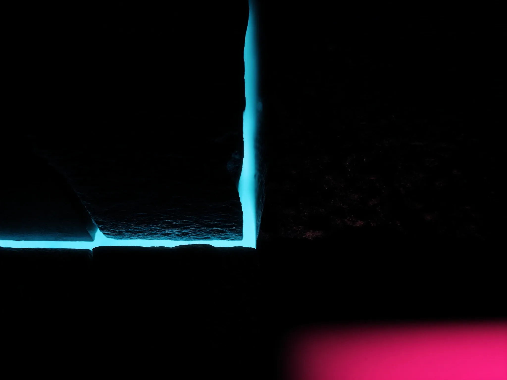 Precision-cut blocks of dark stone fitting perfectly together, a thin line of cyan light along every seam