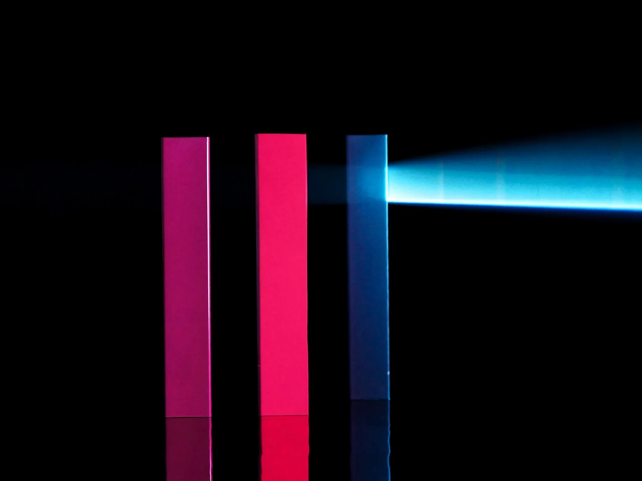 Two precise glass prisms side by side on black, one beam of light passing cleanly from one into the other