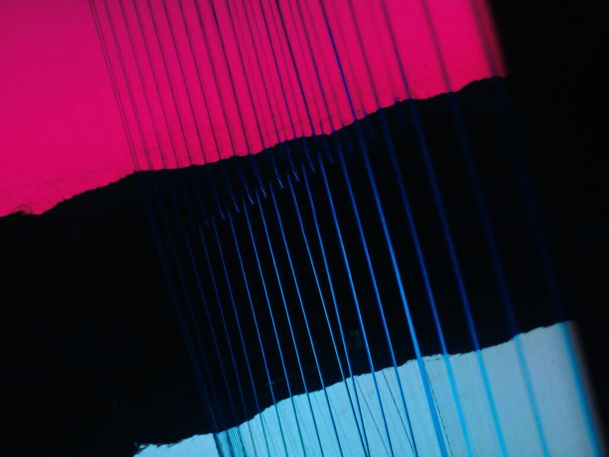 An abstract close crop of suspension-bridge cables at dusk, lines converging, pink sky behind