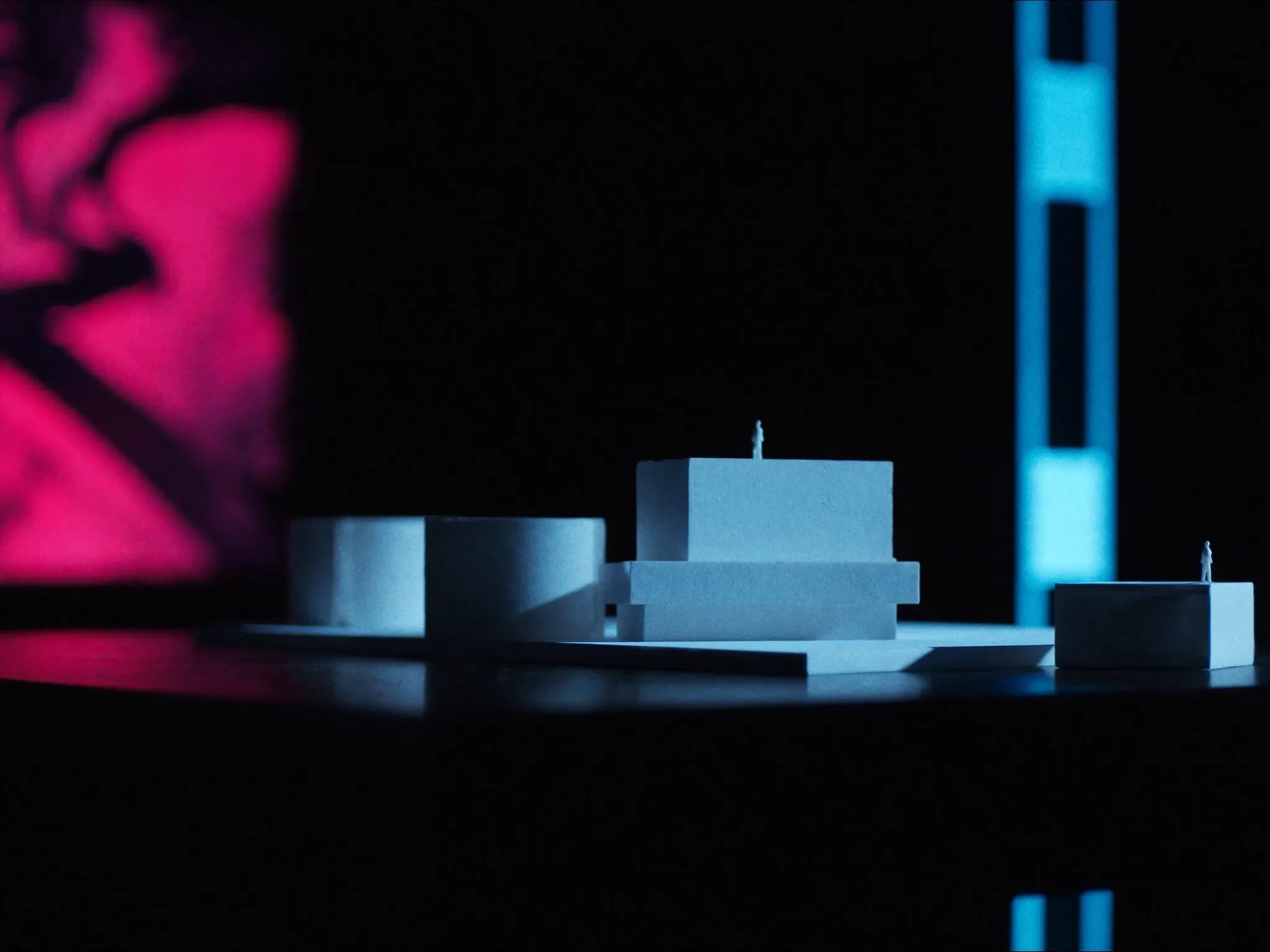 An architectural model of plain white blocks on a dark table, lit dramatically from one side, abstract and precise, no figures, no trees